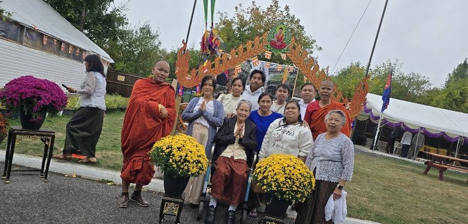 A monk and families beside pots of yellow chrysanthemums at the decorated gateway