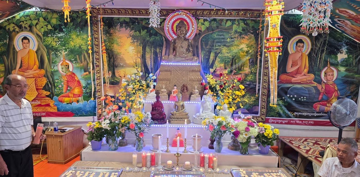 The shrine with its Buddha statue, flowers and candles in front of painted murals